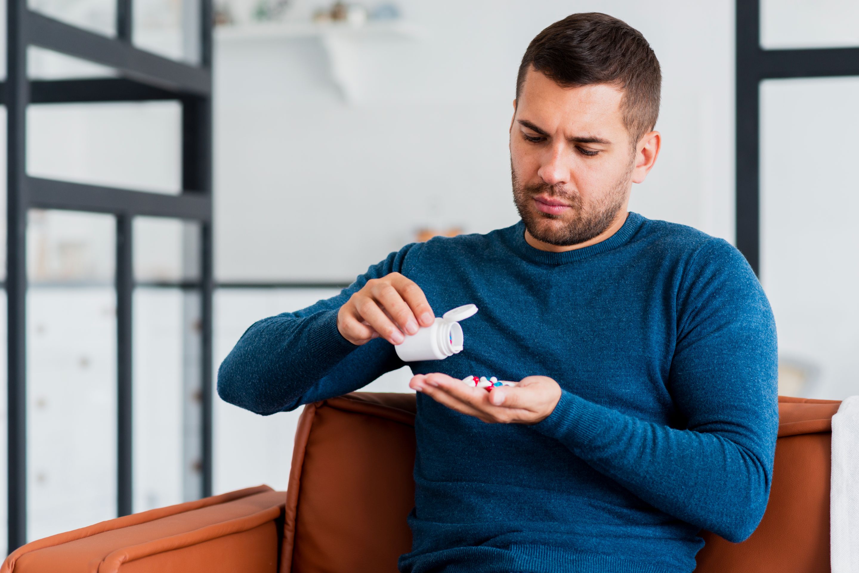 man-home-sitting-couch-taking-pills.jpg