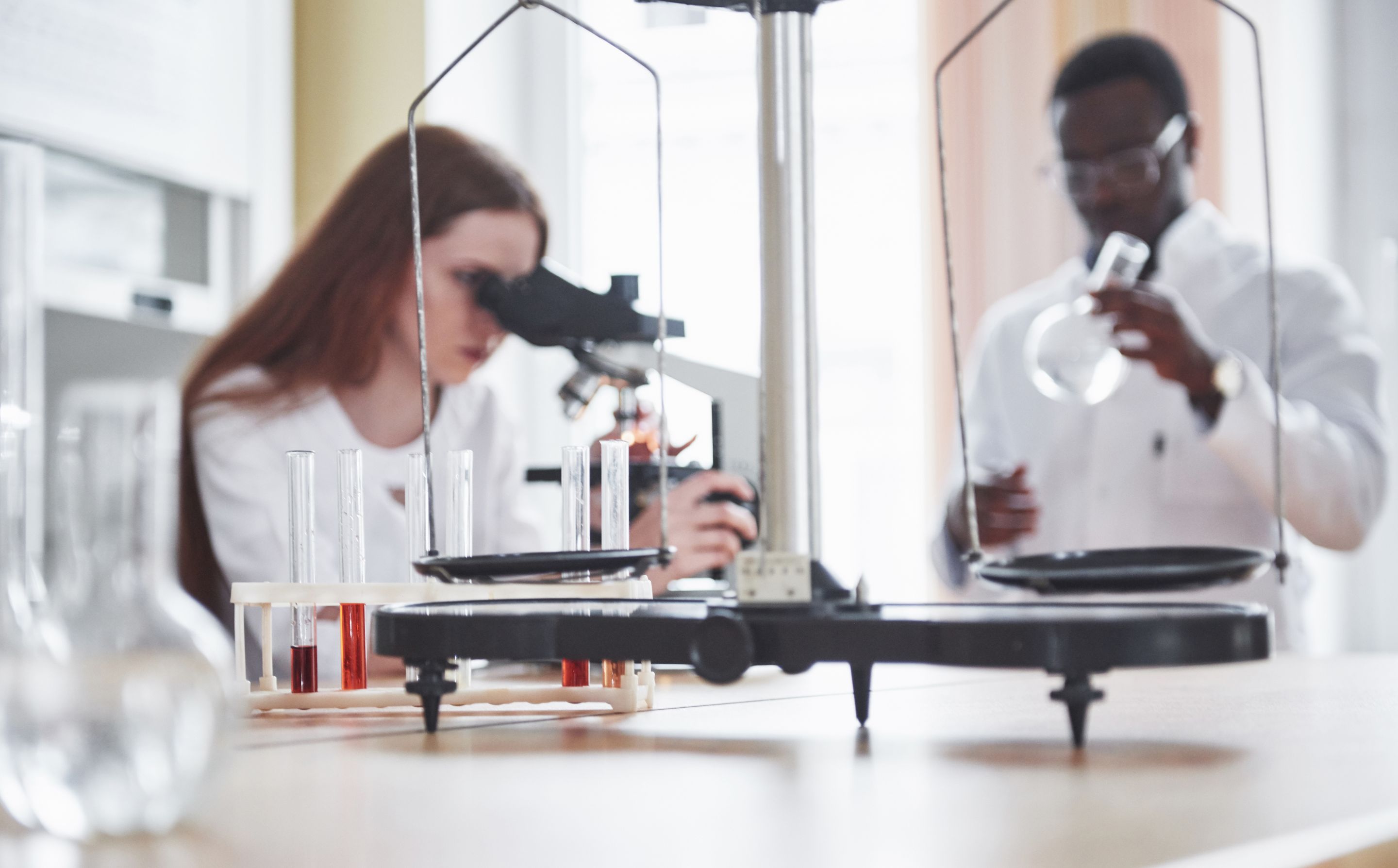 lab-assistant-with-microscope-laboratory-glassware-bulb-with-chemicals.jpg