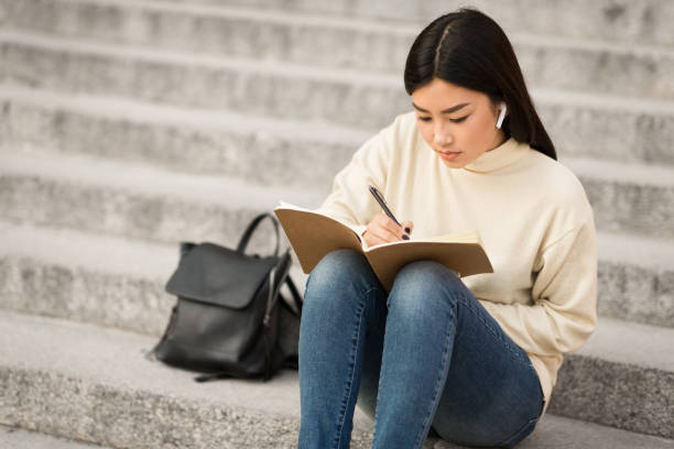 girl-writing-in-diary-sitting-on-the-gray-stairs.jpg
