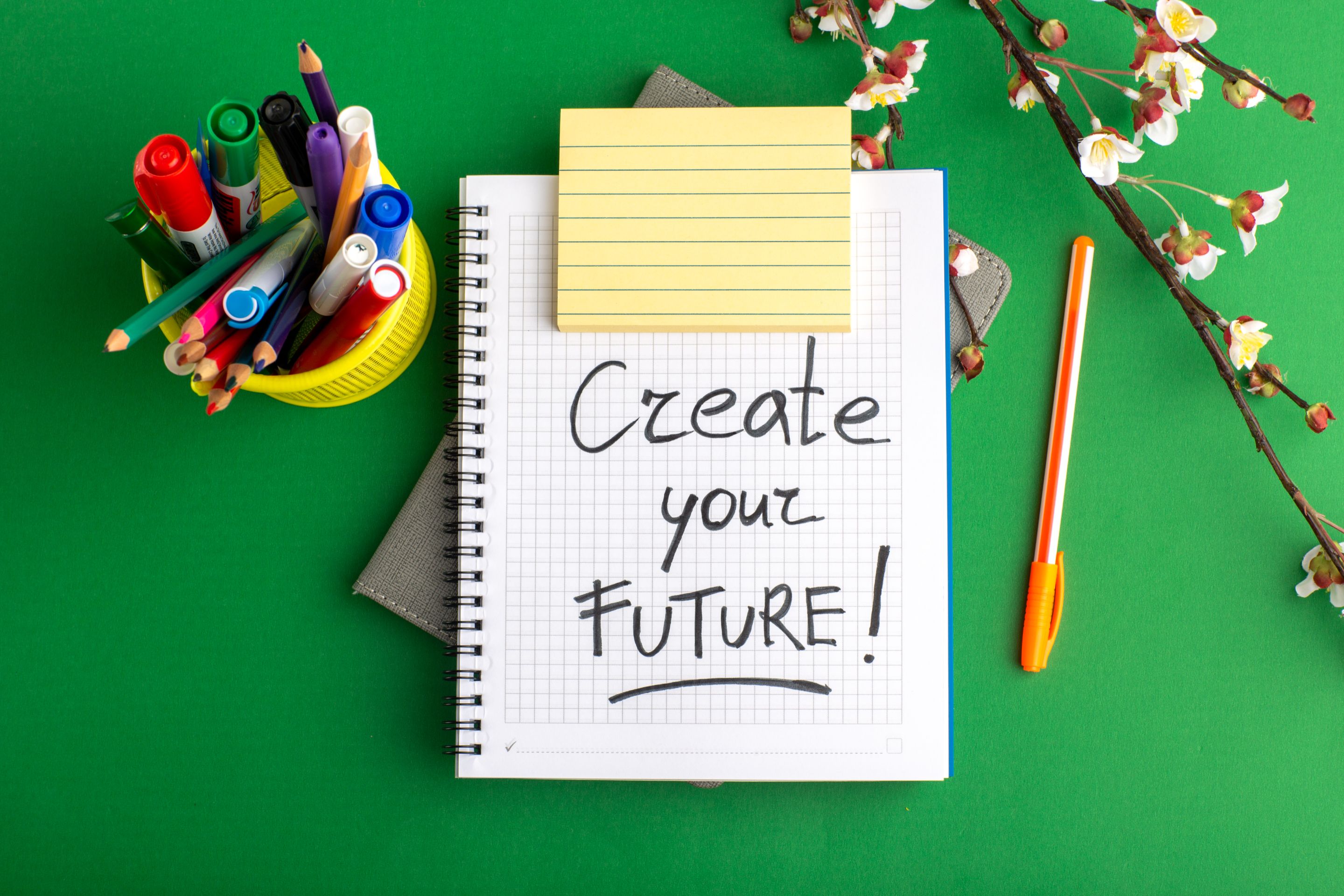 top-view-open-copybook-with-pen-flowers-colorful-felt-pens-green-desk.jpg