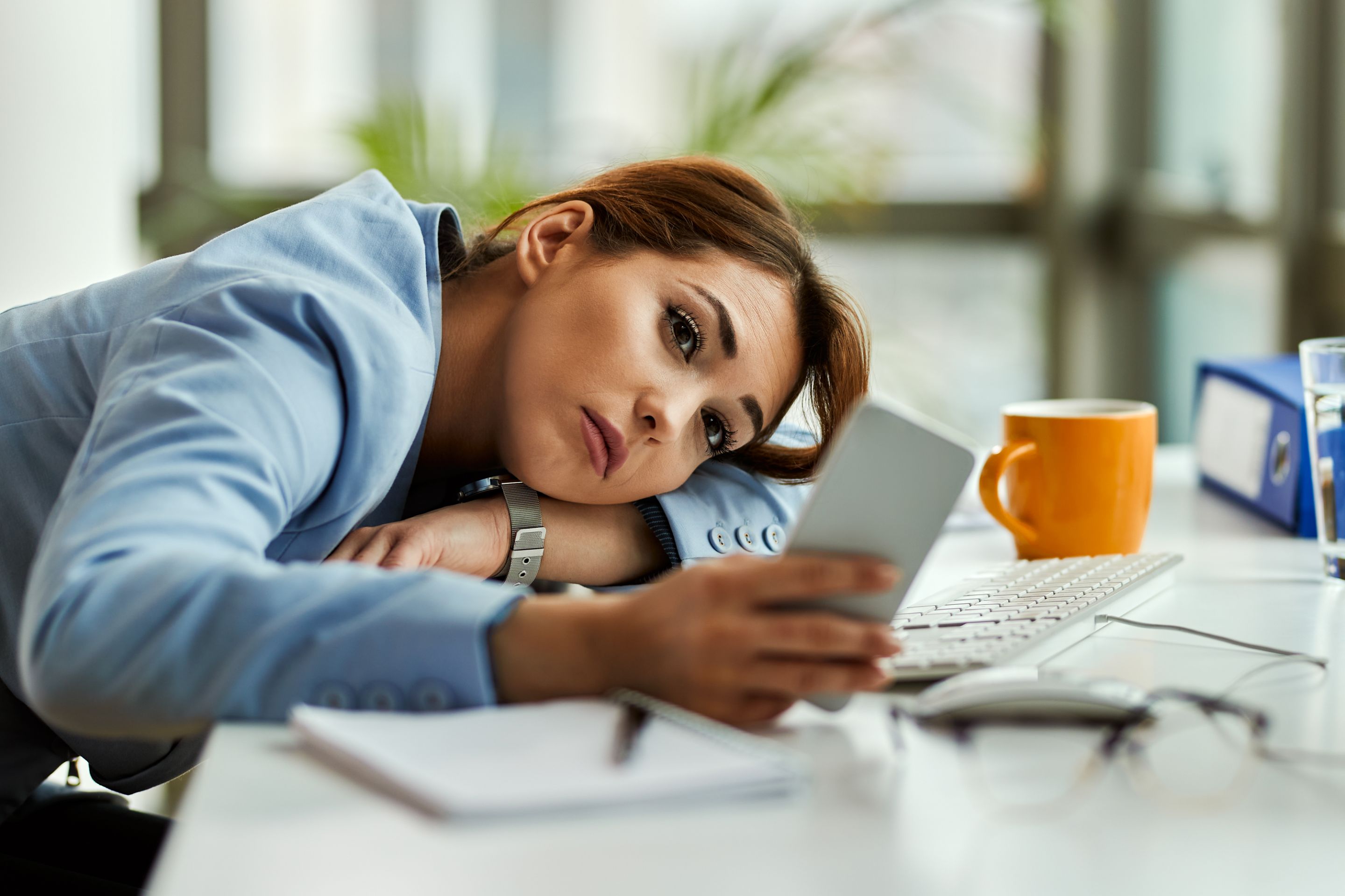 mujer-negocios-pensativa-usando-telefono-movil-mientras-relaja-oficina.jpg